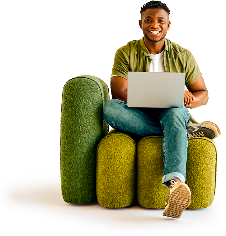 homem negro sentado em um sofá sorrindo com um notebook cinza aberto sob as pernas